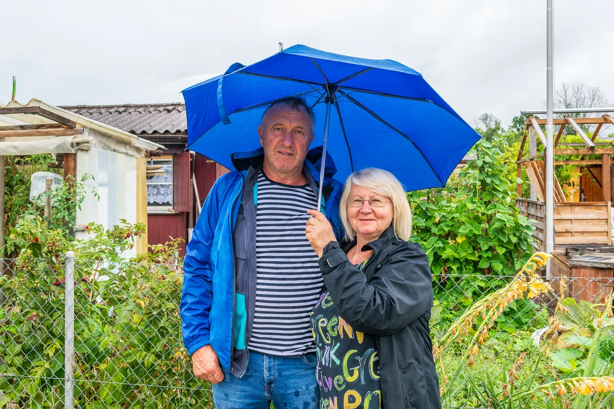 Ein Mann und eine Frau stehen unter einem Regenschirm im Garten.